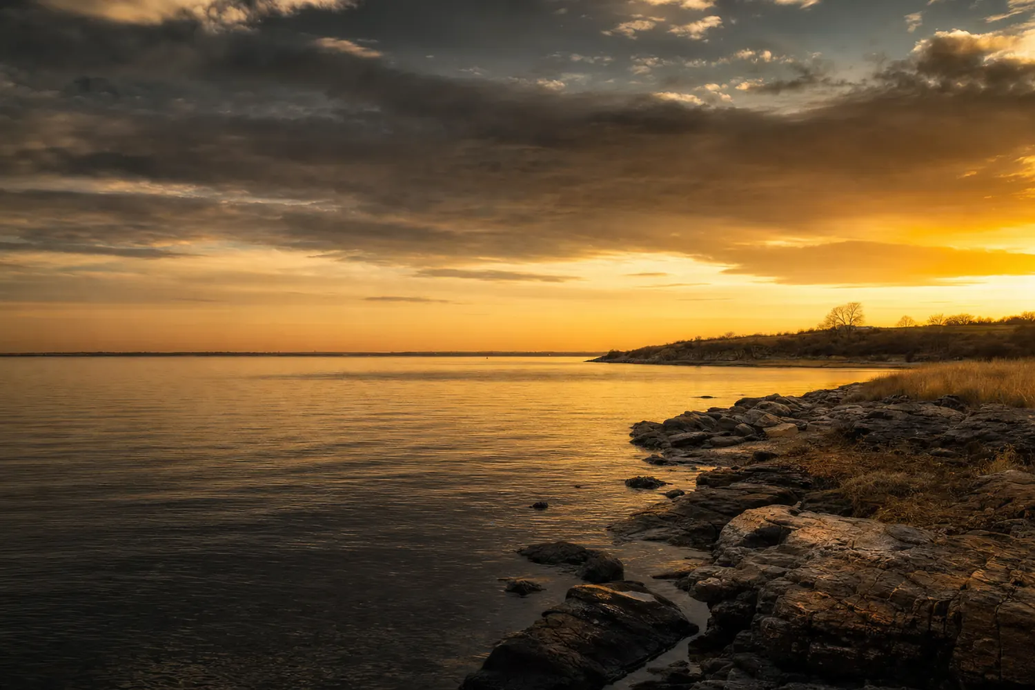 The Long Island Sound shoreline at Bayside at golden hour, calm water and low headland.