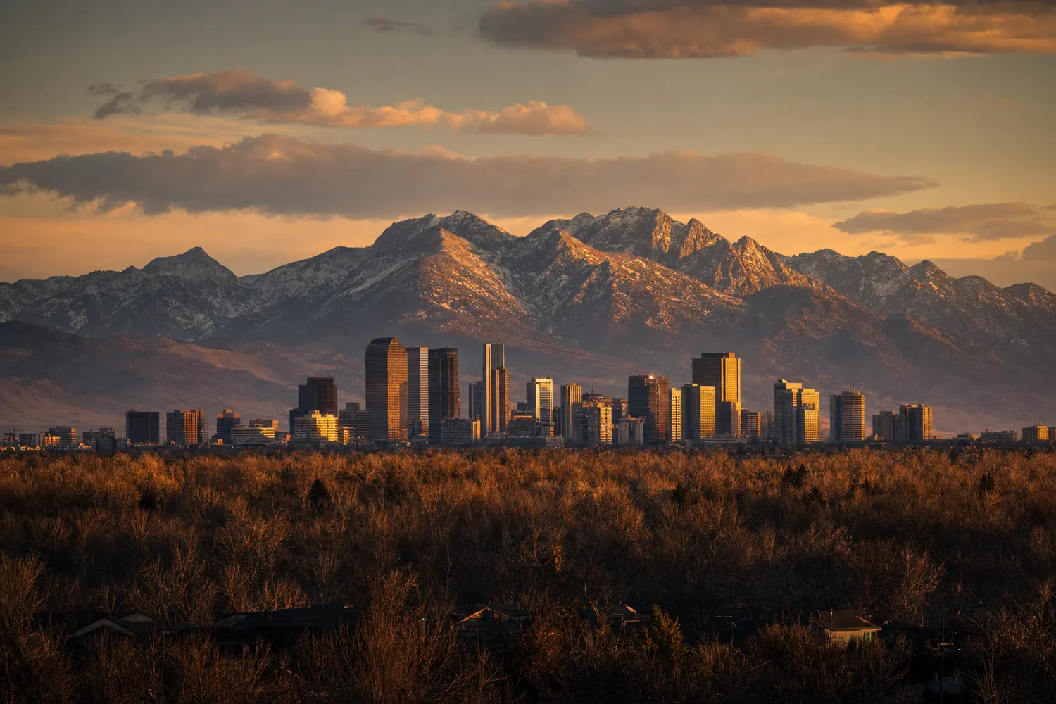 The Front Range of the Rockies rising behind the Denver skyline at sunset.