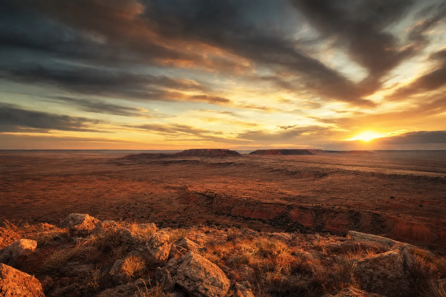 The red earth plains and low mesas of Oklahoma under an enormous sunset sky.